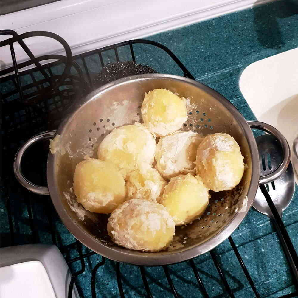 Potatoes in colander for draining and dusting in plain flour